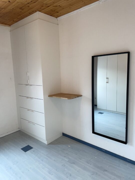 Armoire sur mesure avec tiroirs, placards et planche en bois décorative sur le côté, réalisée par Bois Carré.
